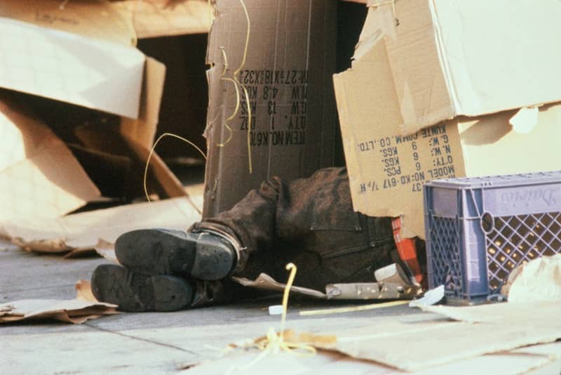 Feet of homeless person sleeping in cardboard box -cm